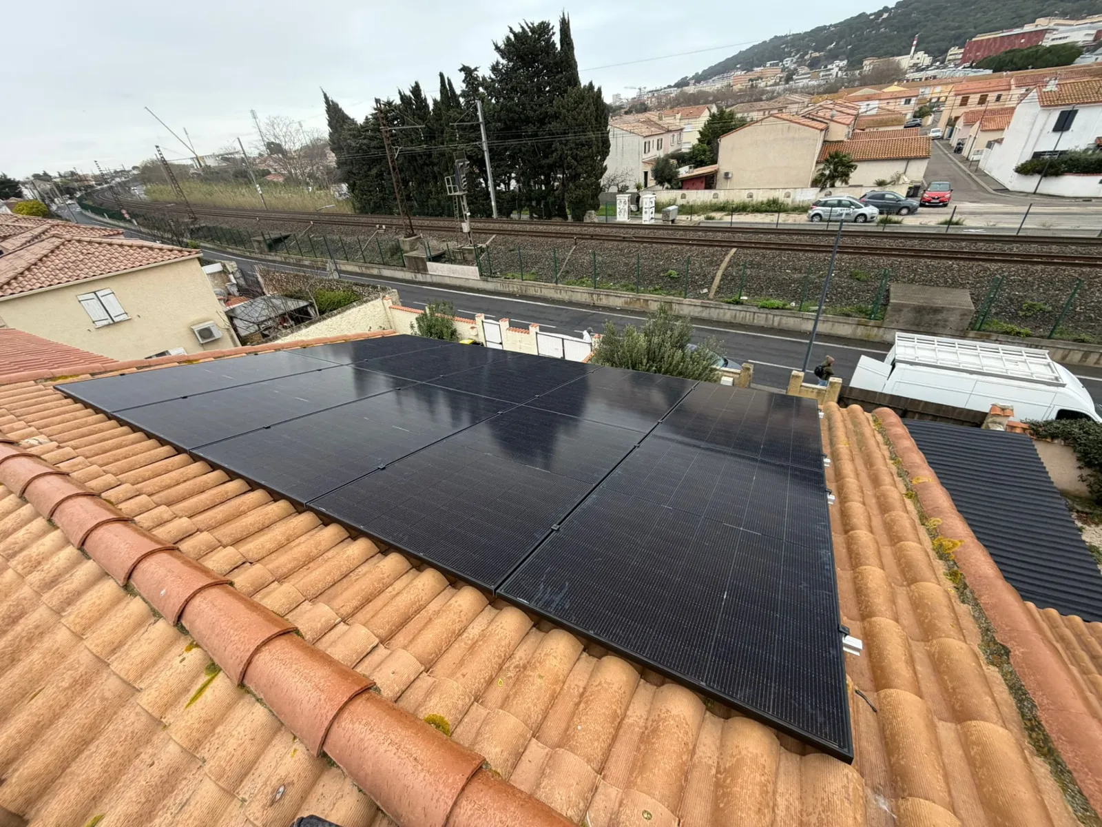 Panneaux photovoltaïques noirs installés sur une toiture en tuiles dans un quartier résidentiel, installation JM Consulting dans l'Hérault
